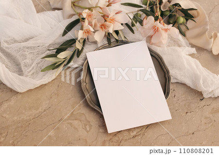 Summer wedding stationery. Birthday mock-up. Blank greeting card, invitation mockup, vintage silver plate. Apricot oleander blossoms. Olive tree branches. Beige marble background. Flat lay, top. 110808201