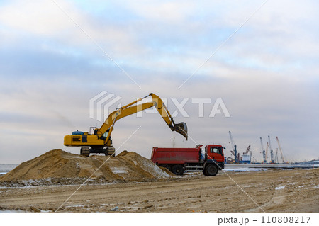 Yellow excavator working on construction site. The road construction. Yellow excavator working on construction site. The road construction. 110808217