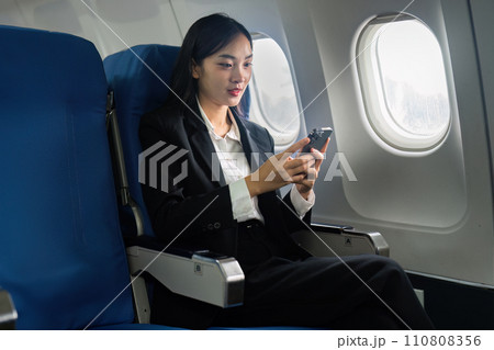 Beautiful Asian businesswoman using mobile phone in aeroplane. working, travel, business concept 110808356