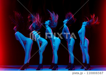Impressive performance. Young women in bodysuits dancing on high heels against black background in neon light Impressive performance. Young women in bodysuits dancing on high heels against black background in neon light 110808387