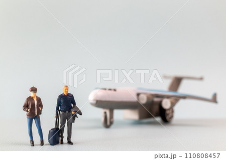 Miniature people, travelers embarks on a delightful vacation, gleefully boarding a tiny airplane Miniature people, travelers embarks on a delightful vacation, gleefully boarding a tiny airplane 110808457