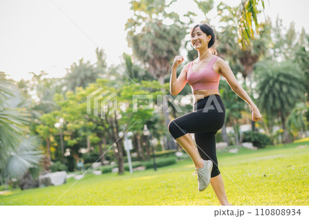 fit 30s Asian woman in her wearing pink sportswear exercising in a public park at sunset. Embrace a healthy outdoor lifestyle and discover the benefits of wellness and well-being. fit 30s Asian woman in her wearing pink sportswear exercising in a public park at sunset. Embrace a healthy outdoor lifestyle and discover the benefits of wellness and well-being. 110808934