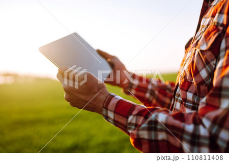 Tablet in the hands of a farmer. Smart farm. Farmer checking his crops on an agricultural field. 110811408