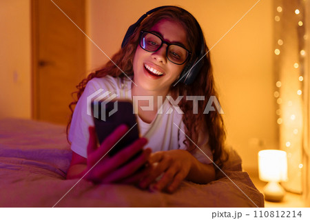 Woman communicates with friends on smartphone in headphones while sitting at home. Freelance concept 110812214