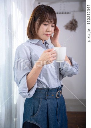 窓際でマグカップを持つ女性 110812345