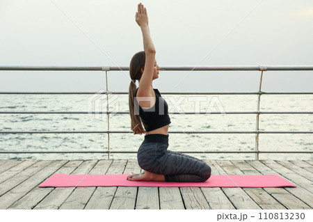 Young girl on yoga mat on wooden floor outdoors 110813230