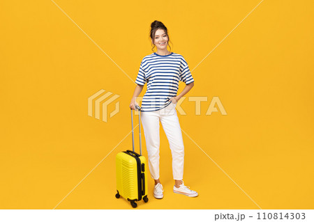 A young girl with a yellow suitcase on a yellow background 110814303