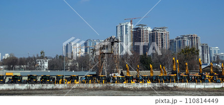Kiev, Ukraine March 18, 2020: Tractors and excavators for sale on the background of houses under construction Kiev, Ukraine March 18, 2020: Tractors and excavators for sale on the background of houses under construction 110814449