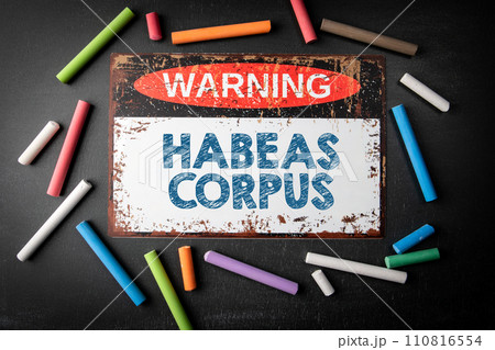 Habeas corpus. Metal warning sign and colored pieces of chalk on a dark chalkboard background 110816554