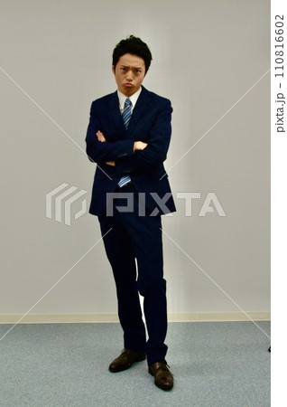 腕を組んで不満顔の若い男性 110816602