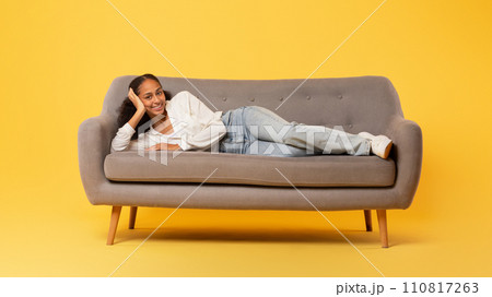Carefree African American teenage girl relaxing lying on sofa, studio Carefree African American teenage girl relaxing lying on sofa, studio 110817263