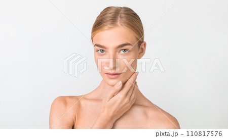 woman with sleek hair and bare shoulders posing in studio 110817576