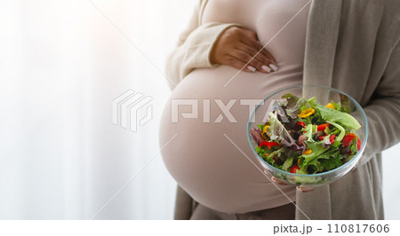 Cropped of black lady expectant holding fresh vegetable salad 110817606