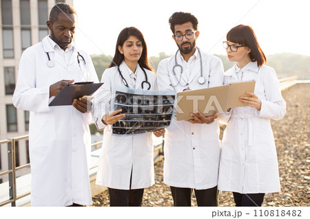 Colleagues coworking with indian man showing results of patient's tests. 110818482