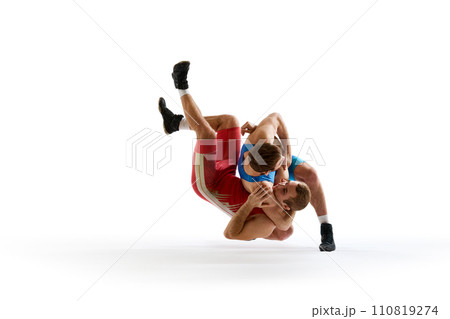 Two strong wrestlers in blue and red wrestling uniform fighting and making hip throw in motion against white studio background. 110819274