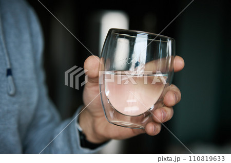 Man drinks water, Close-up shot of man holding glass of fresh water, Quenching thirst, Lifestyle healthcare concept 110819633
