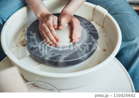 The female hands of a potter model a clay product on a wheel. Pottery craft, shaping a clay product, weekend activity 110820682