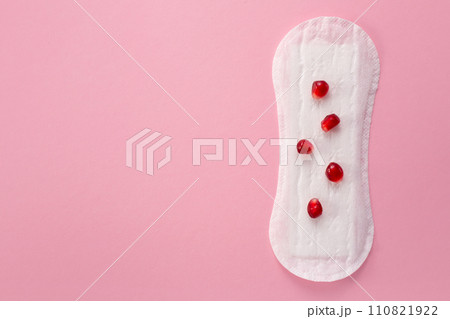Feminine hygiene pad with red pomegranatered menstrual pad on red background. First menstrual period concept. Copy space Feminine hygiene pad with red pomegranatered menstrual pad on red background. First menstrual period concept. Copy space 110821922