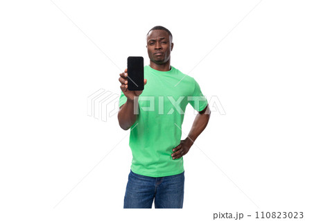young american man dressed in green corporate t-shirt showing smartphone screen young american man dressed in green corporate t-shirt showing smartphone screen 110823023