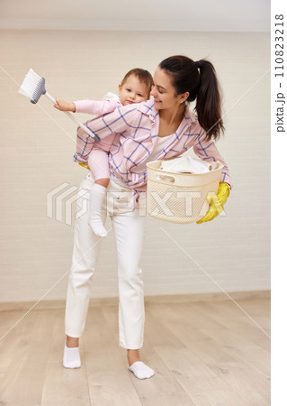 happy mother housewife is holding cute baby girl and basket with laundry at home, Happy family happy mother housewife is holding cute baby girl and basket with laundry at home, Happy family 110823218