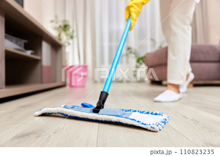 young woman cleaning and mopping floor at living room, daily housekeeping , close-up 110823235