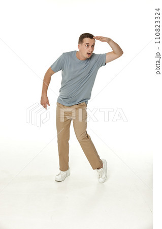 young man looking far away at distance with hand over head on white background 110823324