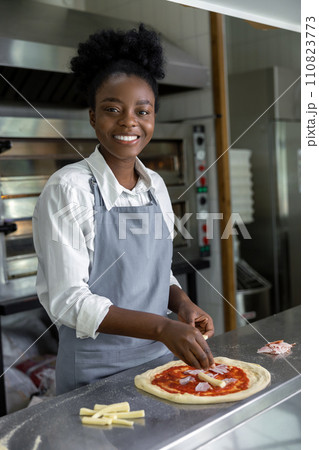 Female pizzeria cook preparing pizza in the kitchen Female pizzeria cook preparing pizza in the kitchen 110823773