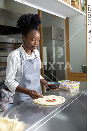 Female pizzeria cook preparing pizza in the kitchen 110823777