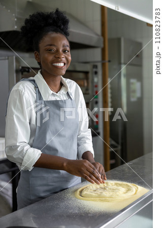 Dark-skinned woman in pizzeria cooking pizza Dark-skinned woman in pizzeria cooking pizza 110823783