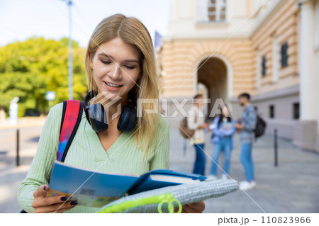 Woman student with books preparing for classes posing outdoor near college. Woman student with books preparing for classes posing outdoor near college. 110823966