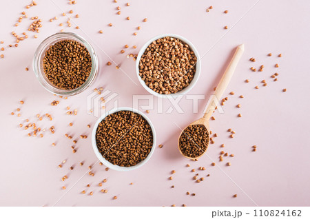 Dry buckwheat tea granules in a bowl, spoon and jar on the table top view 110824162
