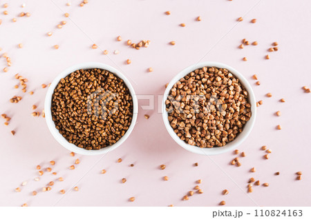 Dry buckwheat tea granules and buckwheat groats in bowls on a pink background top view 110824163