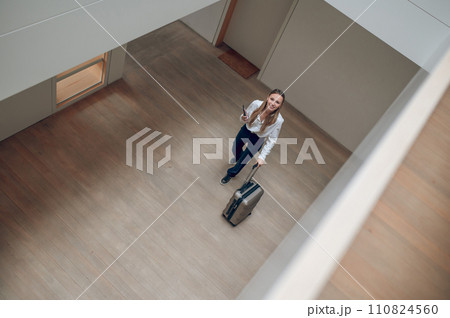 Top view of a girl with a suitcase in a hotel hall Top view of a girl with a suitcase in a hotel hall 110824560