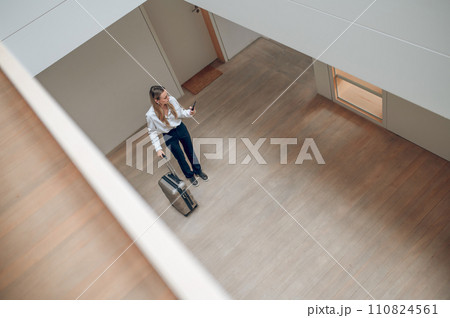 Top view of a girl with a suitcase in a hotel hall Top view of a girl with a suitcase in a hotel hall 110824561