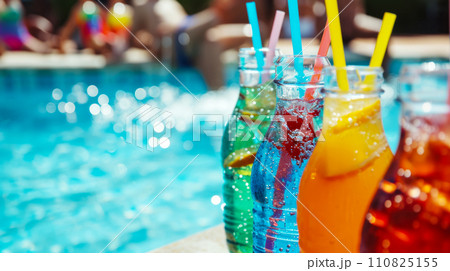 Bottles with your favorite multi-colored natural soft drinks against the backdrop of the pool, concept for advertising refreshing lemonades and juices at a student party in the pool Bottles with your favorite multi-colored natural soft drinks against the backdrop of the pool, concept for advertising refreshing lemonades and juices at a student party in the pool 110825155