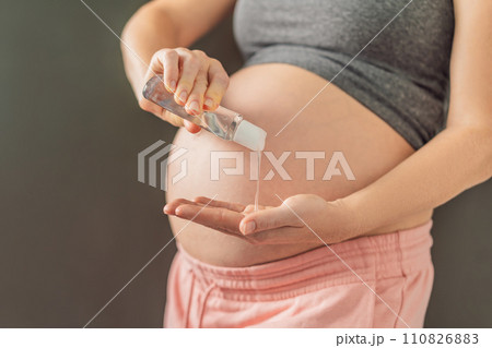 Expectant mom ensures safety, applying gel sanitizer for a clean and healthy pregnancy 110826883