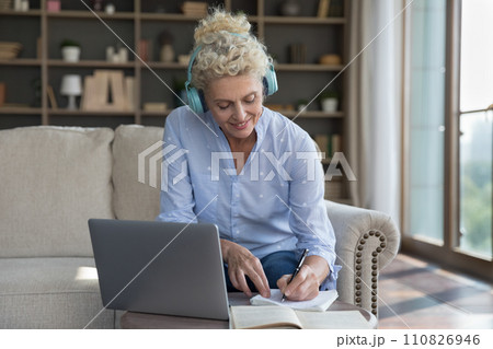 Smiling attractive middle aged female e-learning using laptop 110826946