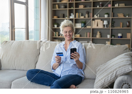 Woman holding card using electronic bank application buying on internet Woman holding card using electronic bank application buying on internet 110826965