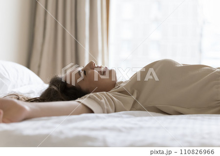Close up happy young 30s woman lying on bed Close up happy young 30s woman lying on bed 110826966