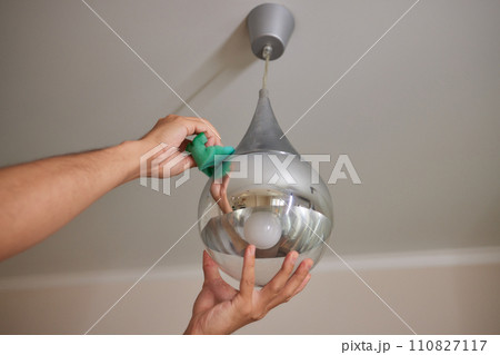 Extreme close-up of unrecognizable man cleaning electric lamp with wet microfiber rag. Close-up of male hands wiping chandelier removing dust at home. Concept of cleaning and household, slow motion. Extreme close-up of unrecognizable man cleaning electric lamp with wet microfiber rag. Close-up of male hands wiping chandelier removing dust at home. Concept of cleaning and household, slow motion. 110827117