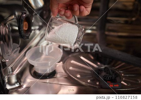 High-angle view of unrecognizable man using funnel to pour granulated salt to soften hard water into dishwasher hole 110827158