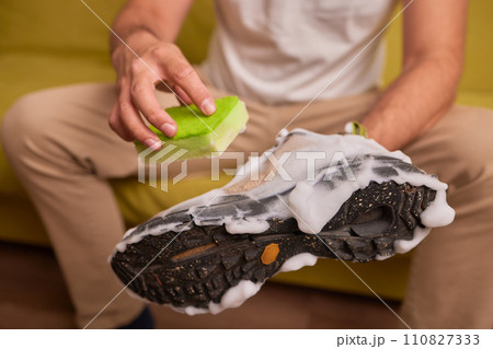 Cleaning suede sneakers. A worker in a shoe workshop cleans a pile of shoes Cleaning suede sneakers. A worker in a shoe workshop cleans a pile of shoes 110827333