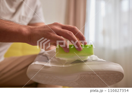 Cleaning suede sneakers. A worker in a shoe workshop cleans a pile of shoes 110827354