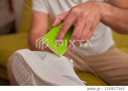 Cleaning suede sneakers. A worker in a shoe workshop cleans a pile of shoes 110827362