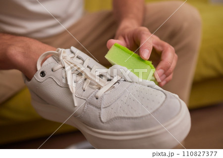 Cleaning suede sneakers. A worker in a shoe workshop cleans a pile of shoes Cleaning suede sneakers. A worker in a shoe workshop cleans a pile of shoes 110827377
