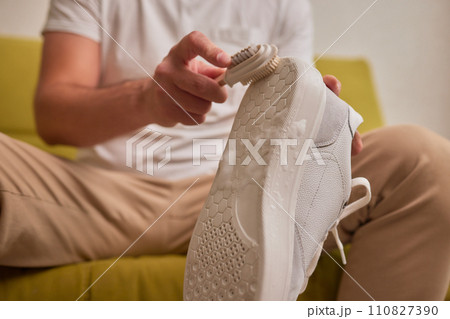 Cleaning suede sneakers. A worker in a shoe workshop cleans a pile of shoes 110827390