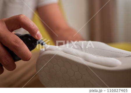 Cleaning suede sneakers. A worker in a shoe workshop cleans a pile of shoes 110827405
