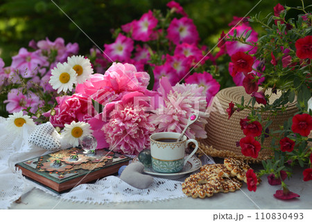 Beautiful still life with peony flowers, vintage cup and cookies on the table. Romantic greeting card for birthday, Valentines, Mothers Day concept. Summer background with vintage objects Beautiful still life with peony flowers, vintage cup and cookies on the table. Romantic greeting card for birthday, Valentines, Mothers Day concept. Summer background with vintage objects 110830493