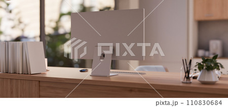 A modern and comfortable indoors workspace with a PC computer snd accessories on a wooden table. 110830684