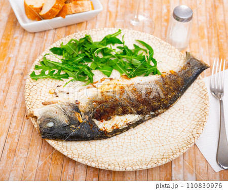Grilled sea bass fish served with arugula Grilled sea bass fish served with arugula 110830976